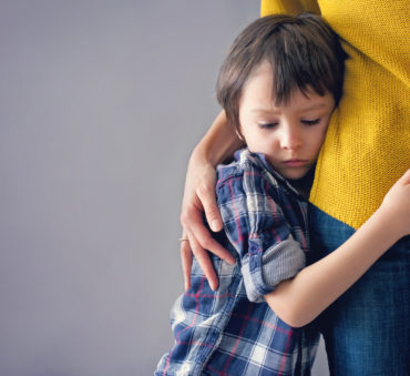 A sad little boy hugging his mother and not wanting to leave with his father represents how a Chicago child custody attorney can help you keep your children.