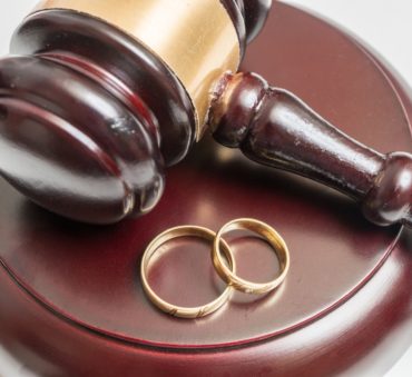 This is a closeup view of a gavel and wedding rings representing how a Chicago family law attorney can help obtain a divorce.