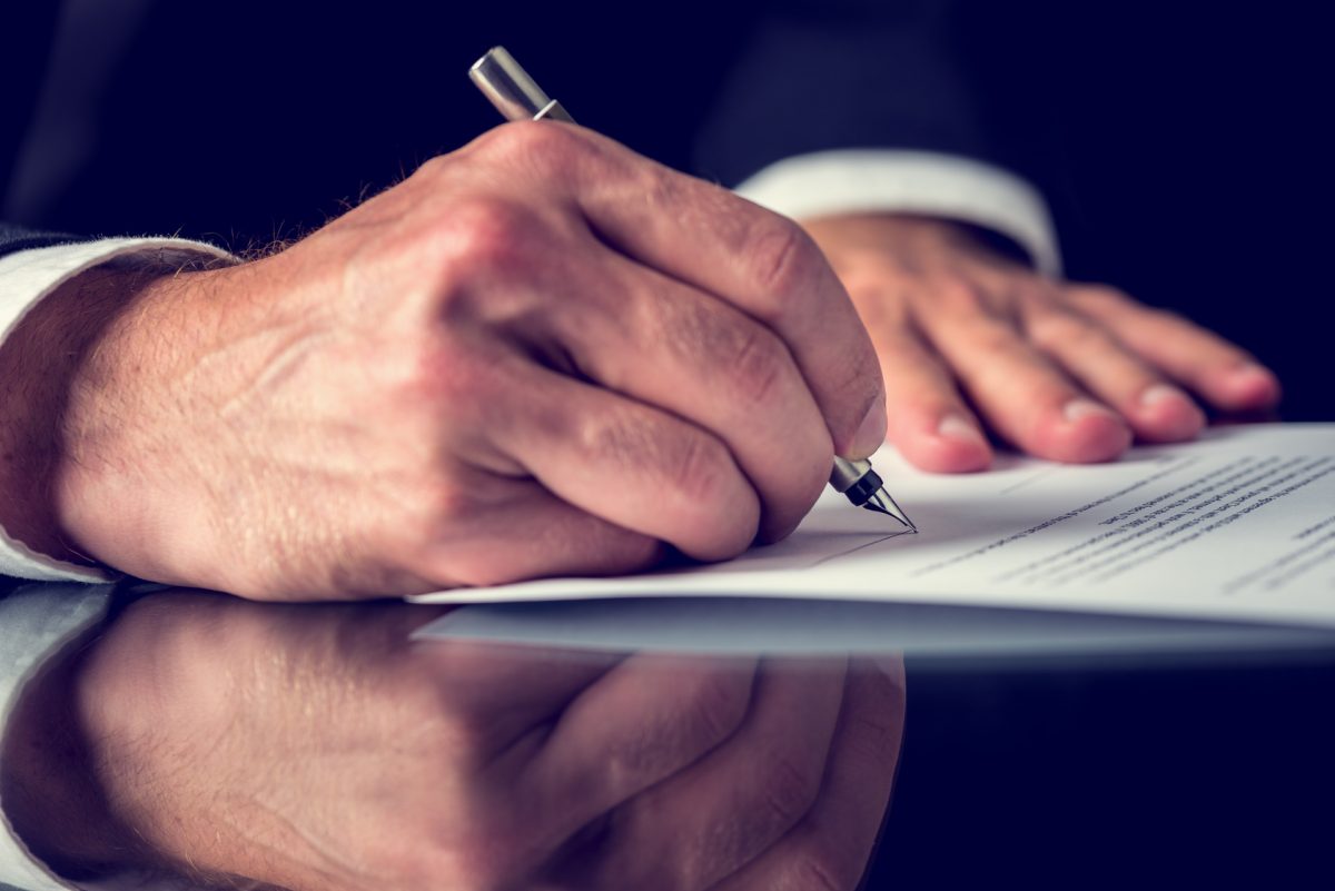 This is a closeup of a male hand signing a power of attorney document with a Lake Forest divorce attorney.