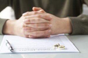 ife signs divorce decree form with ring after speaking with a wheaton divorce lawyer