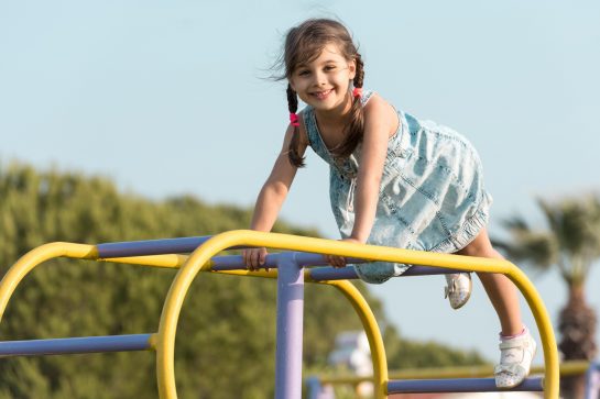 Child Girl Playing At Playground Outdoors In Summer