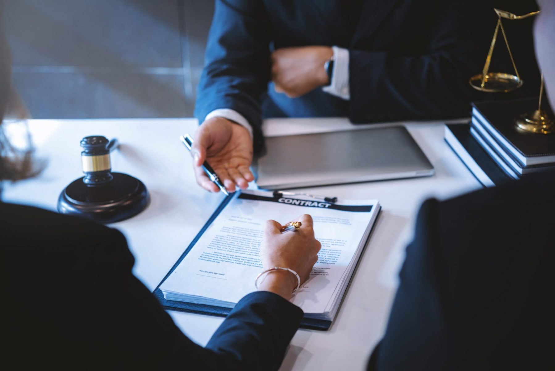 Women signing divorce papers at a lawyer's office representing the need for Northbrook divorce attorneys.