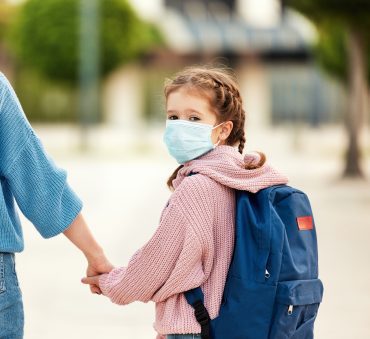 A girl that is wearing a mask and holding her mother's hand, speak to Cook County Child Custody Lawyer to change your parenting plan during the pandemic.