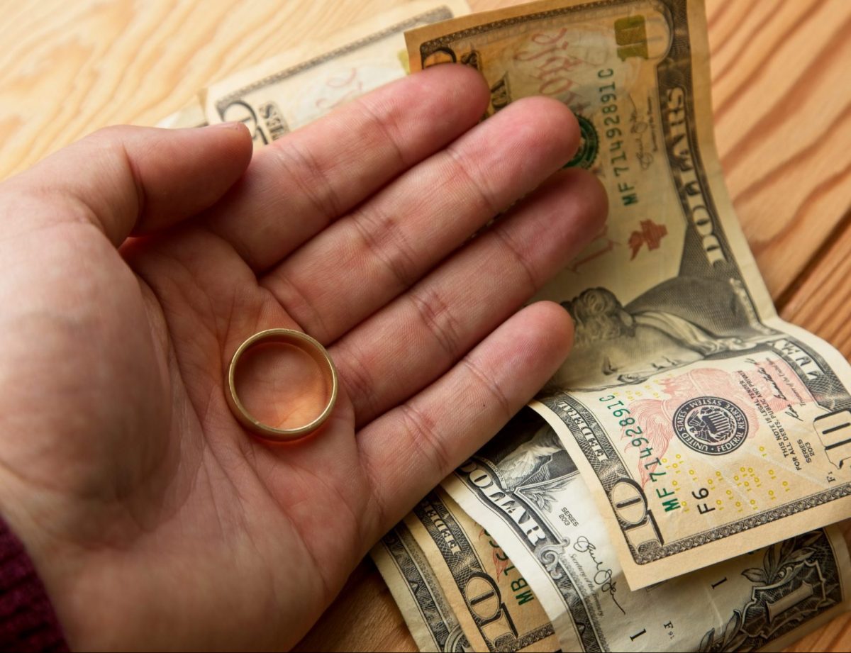 Wedding band in hand with money on table, needing good Divorce attorneys Chicago to look over alimony case.
