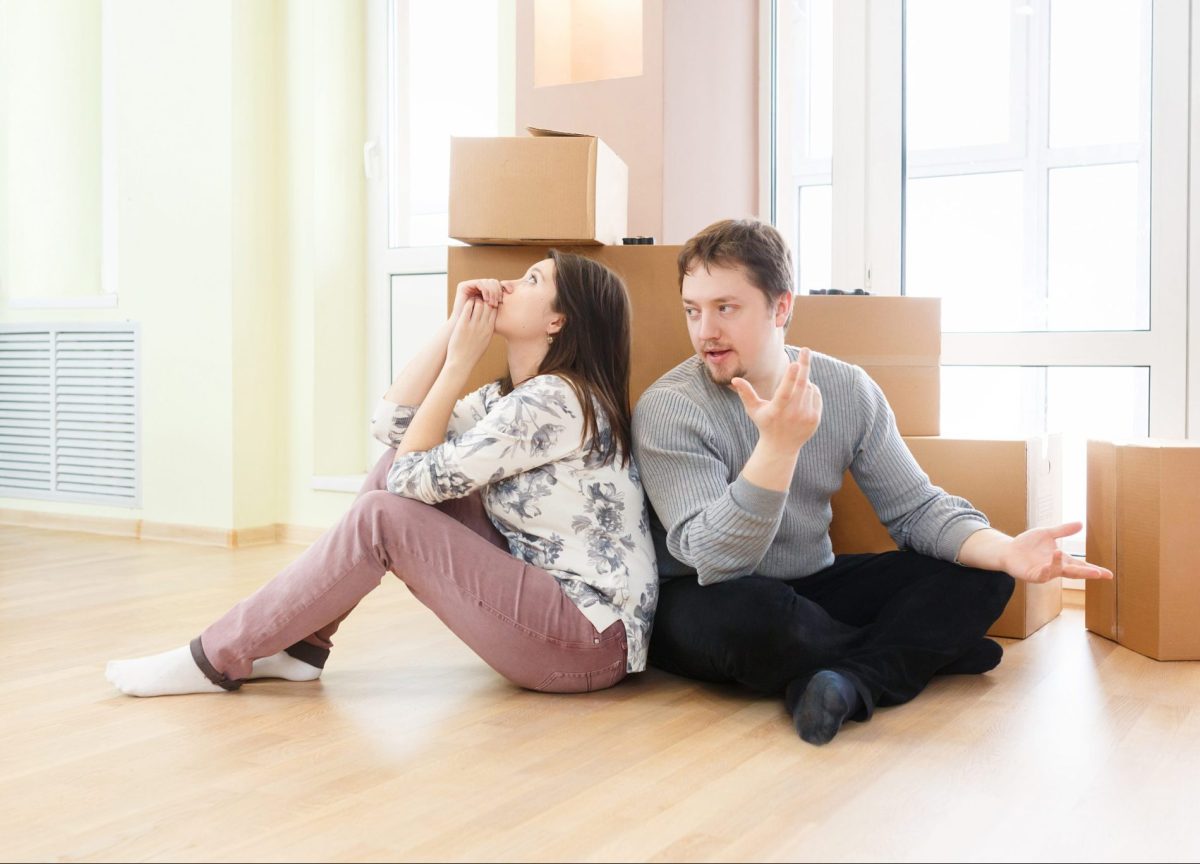 Couple sitting back to back with boxes arguing when needing Divorce Lawyers Glenview.