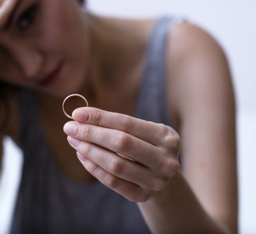 Woman thinking of divorce holding wedding band, concept for meeting with Divorce Attorney Chicago.